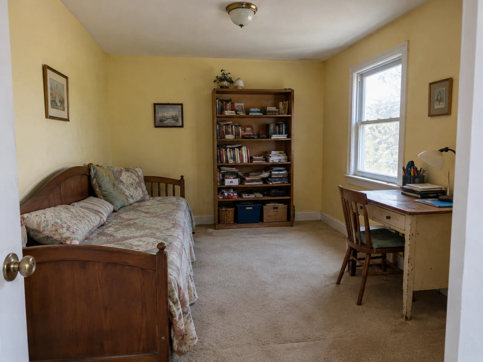Dated guest bedroom with daybed, mismatched desk, and cluttered bookcase